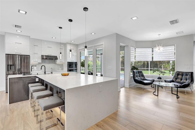 5285 Far Oak Cir, Sarasota, FL 34238 - kitchen with modern cabinets, under cabinet range hood, white cabinetry, stainless steel refrigerator with ice dispenser, and light countertops