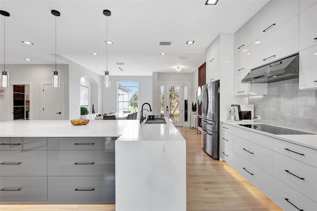 5285 Far Oak Cir, Sarasota, FL 34238 - kitchen featuring under cabinet range hood, black electric cooktop, modern cabinets, freestanding refrigerator, and a sink