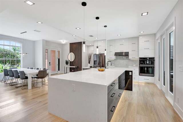 5285 Far Oak Cir, Sarasota, FL 34238 - kitchen with modern cabinets, under cabinet range hood, double oven, white cabinetry, and light wood-type flooring