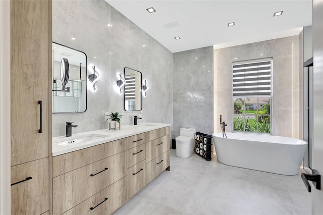 5285 Far Oak Cir, Sarasota, FL 34238 - bathroom featuring double vanity, a freestanding bath, toilet, concrete floors, and tile walls