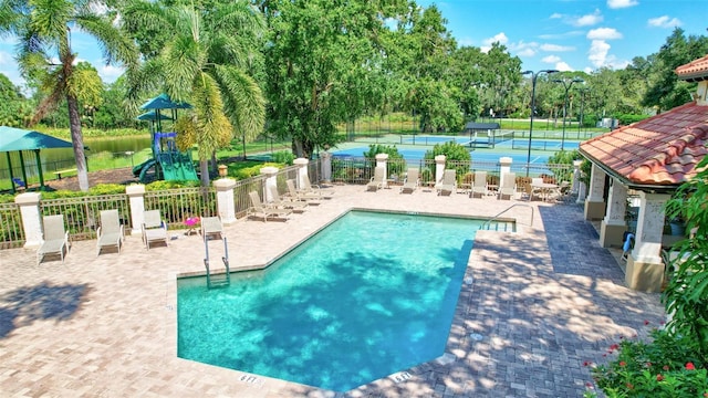 5285 Far Oak Cir, Sarasota, FL 34238 - community pool with a tennis court, view of wooded area, and a patio area