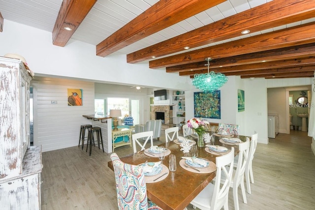 102 77th St, Holmes Beach, FL 34217 - dining space with wood finished floors, a stone fireplace, and beamed ceiling