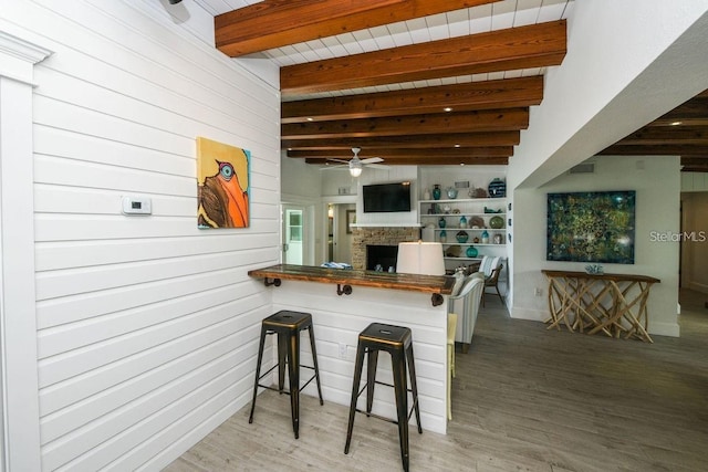 102 77th St, Holmes Beach, FL 34217 - kitchen with beamed ceiling, a ceiling fan, wood finished floors, a fireplace, and a breakfast bar area