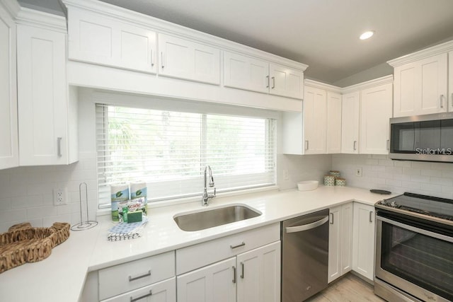 102 77th St, Holmes Beach, FL 34217 - kitchen with stainless steel appliances, a sink, white cabinetry, light countertops, and recessed lighting