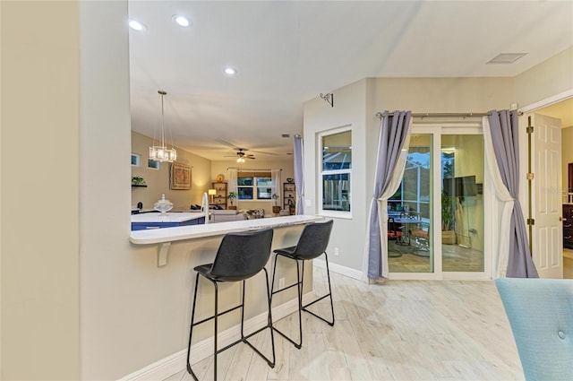 12175 Maple Ridge Dr, Parrish, FL 34219 - kitchen with light wood-type flooring, a kitchen breakfast bar, light countertops, recessed lighting, and a ceiling fan