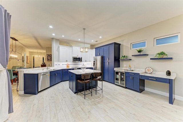 12175 Maple Ridge Dr, Parrish, FL 34219 - kitchen with appliances with stainless steel finishes, beverage cooler, a chandelier, a breakfast bar area, and light wood-type flooring