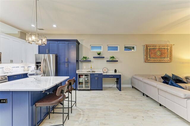 12175 Maple Ridge Dr, Parrish, FL 34219 - kitchen featuring stainless steel refrigerator with ice dispenser, blue cabinets, beverage cooler, open floor plan, and a breakfast bar area