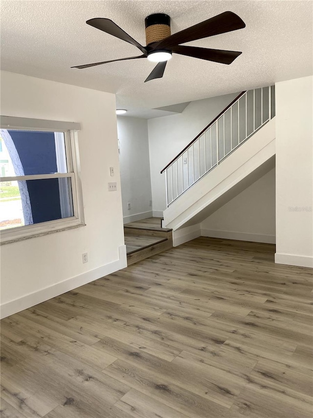 1947 Los Lomas Dr, Clearwater, FL 33763 - unfurnished living room with a textured ceiling, ceiling fan, wood finished floors, stairs, and baseboards