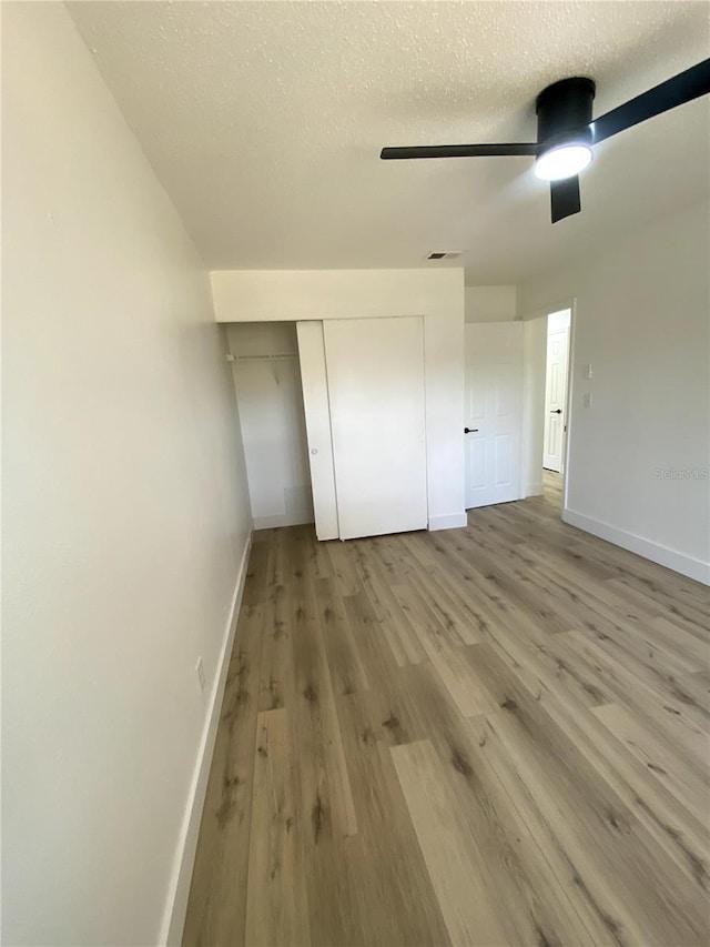 1947 Los Lomas Dr, Clearwater, FL 33763 - unfurnished bedroom with baseboards, wood finished floors, a closet, a textured ceiling, and a ceiling fan
