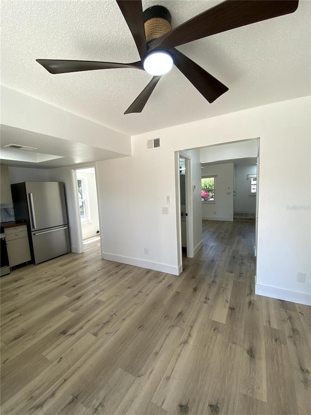 1947 Los Lomas Dr, Clearwater, FL 33763 - unfurnished living room featuring a ceiling fan, light wood-type flooring, baseboards, and a textured ceiling