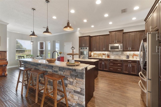 2350 Virgil Hall Rd, Lithia, FL 33547 - kitchen with stainless steel appliances, an island with sink, ornamental molding, a kitchen breakfast bar, and dark brown cabinets