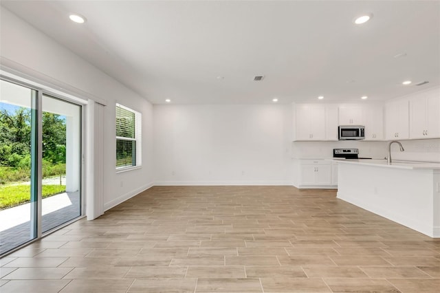 5213 Patano Loop, Palmetto, FL 34221 - unfurnished living room with recessed lighting, baseboards, light wood-style floors, and a sink