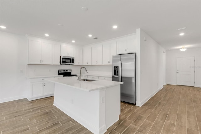 5213 Patano Loop, Palmetto, FL 34221 - kitchen with stainless steel appliances, a sink, light wood-type flooring, an island with sink, and light countertops