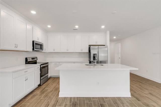5213 Patano Loop, Palmetto, FL 34221 - kitchen with stainless steel appliances, a kitchen island with sink, light wood-style floors, light countertops, and recessed lighting