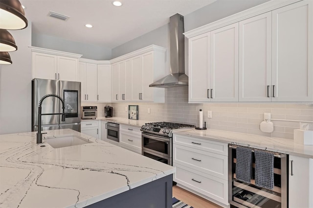 8020 Clearwater Ct, Sarasota, FL 34241 - kitchen featuring wall chimney exhaust hood, appliances with stainless steel finishes, wine cooler, white cabinets, and recessed lighting