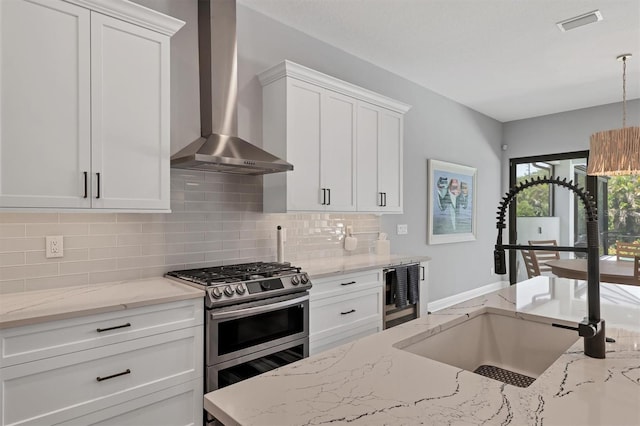 8020 Clearwater Ct, Sarasota, FL 34241 - kitchen featuring wall chimney exhaust hood, double oven range, a sink, decorative backsplash, and white cabinets