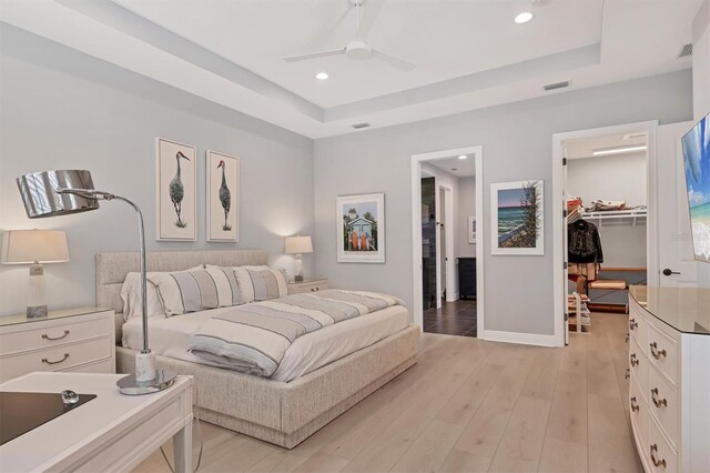 8020 Clearwater Ct, Sarasota, FL 34241 - bedroom with a spacious closet, a tray ceiling, recessed lighting, and light wood-type flooring