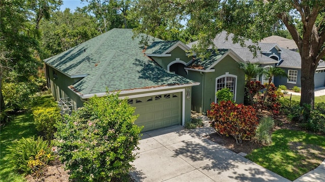 135 Tall Trees Ct, Sarasota, FL 34232 - view of front of house with a shingled roof, stucco siding, an attached garage, and concrete driveway