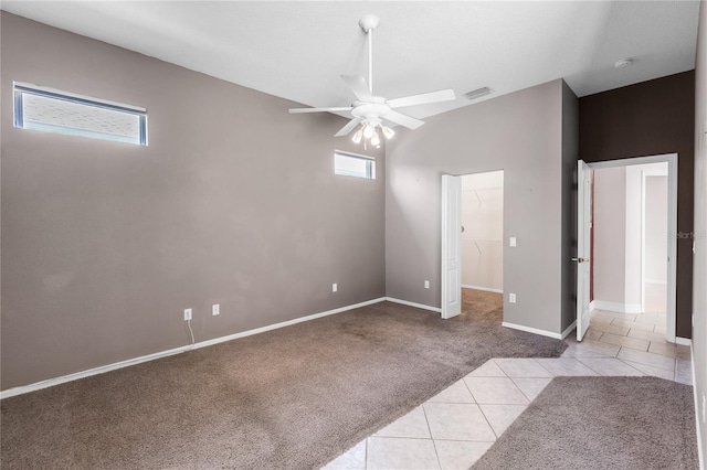 135 Tall Trees Ct, Sarasota, FL 34232 - unfurnished bedroom featuring light tile patterned flooring, light carpet, a spacious closet, baseboards, and a ceiling fan
