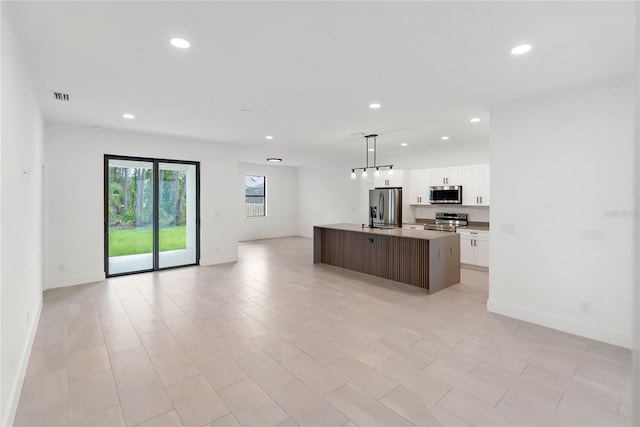 2638 Hagerick Ln, North Port, FL 34288 - kitchen with stainless steel appliances, open floor plan, recessed lighting, white cabinetry, and an island with sink