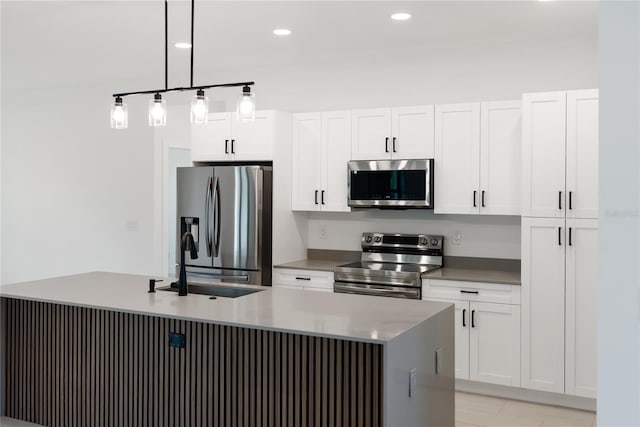 2638 Hagerick Ln, North Port, FL 34288 - kitchen featuring appliances with stainless steel finishes, white cabinetry, hanging light fixtures, an island with sink, and a sink