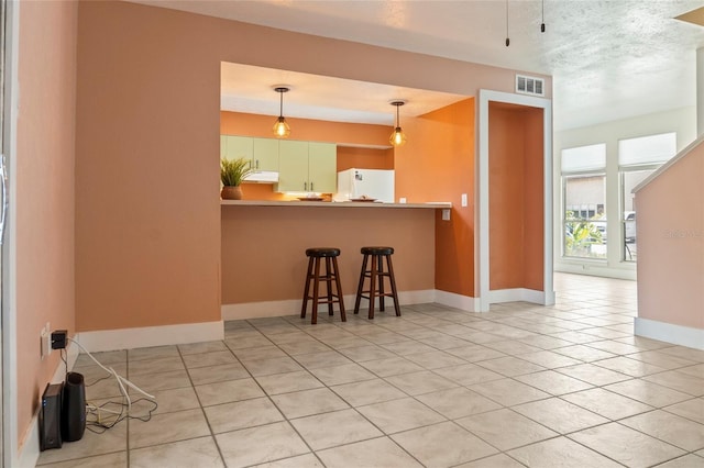 4475 Sandner Dr, Sarasota, FL 34243 - kitchen with freestanding refrigerator, a breakfast bar area, light tile patterned floors, baseboards, and decorative light fixtures