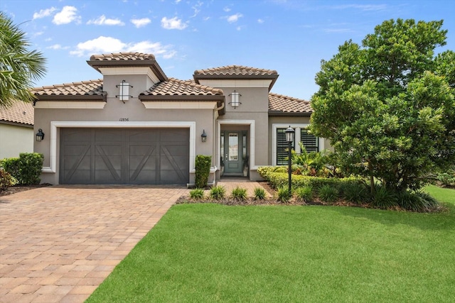 12856 Sorrento Way, Bradenton, FL 34211 - mediterranean / spanish-style house with a front yard, an attached garage, driveway, stucco siding, and a tiled roof