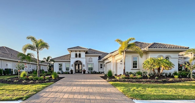 7838 Bowspirit Way, Lakewood Ranch, FL 34202 - view of front facade featuring french doors, an attached garage, decorative driveway, stucco siding, and a front yard