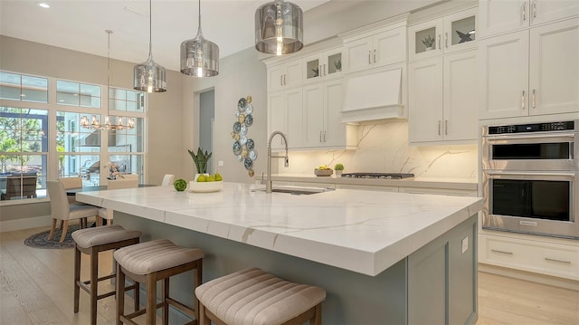 7838 Bowspirit Way, Lakewood Ranch, FL 34202 - kitchen with a sink, double oven, premium range hood, light stone countertops, and a chandelier