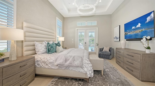 7838 Bowspirit Way, Lakewood Ranch, FL 34202 - bedroom with a chandelier, access to outside, light wood finished floors, a tray ceiling, and a high ceiling