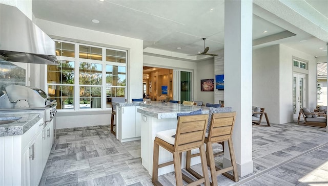 7838 Bowspirit Way, Lakewood Ranch, FL 34202 - kitchen with exhaust hood, white cabinetry, light stone counters, recessed lighting, and ceiling fan