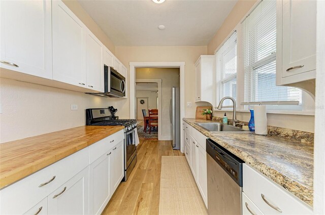 2509 8th Ave W, Bradenton, FL 34205 - kitchen with stainless steel appliances, a sink, white cabinetry, light wood-type flooring, and wood counters