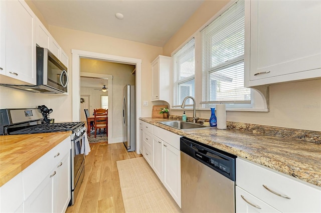 2509 8th Ave W, Bradenton, FL 34205 - kitchen featuring appliances with stainless steel finishes, a sink, butcher block counters, white cabinetry, and light wood-style flooring