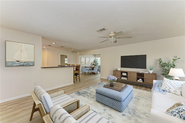5223 Shadow Lawn Dr, Sarasota, FL 34242 - living area featuring a ceiling fan, light wood-type flooring, baseboards, and a textured ceiling