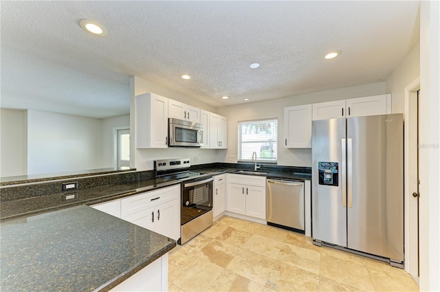 5223 Shadow Lawn Dr, Sarasota, FL 34242 - kitchen featuring stainless steel appliances, a sink, white cabinetry, dark stone counters, and recessed lighting