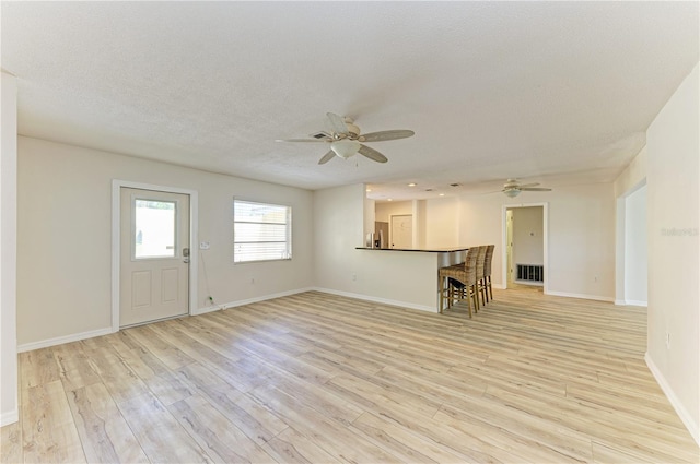 5223 Shadow Lawn Dr, Sarasota, FL 34242 - unfurnished living room featuring ceiling fan, light wood-style flooring, baseboards, and a textured ceiling