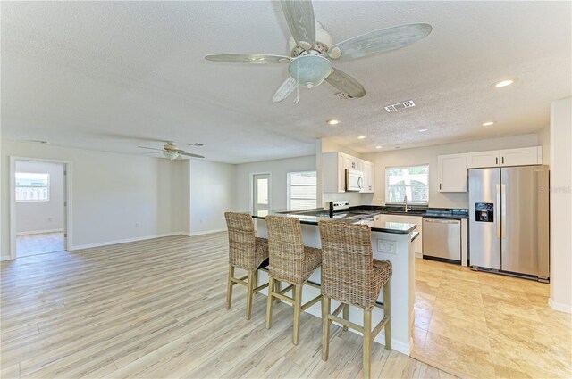 5223 Shadow Lawn Dr, Sarasota, FL 34242 - kitchen featuring appliances with stainless steel finishes, a ceiling fan, a textured ceiling, dark countertops, and white cabinets