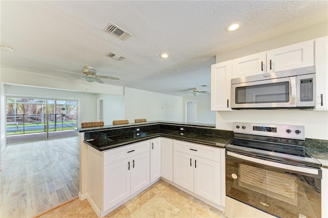 5223 Shadow Lawn Dr, Sarasota, FL 34242 - kitchen featuring appliances with stainless steel finishes, a ceiling fan, a peninsula, white cabinetry, and a textured ceiling