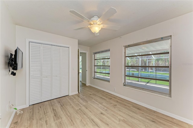 5223 Shadow Lawn Dr, Sarasota, FL 34242 - unfurnished bedroom featuring light wood finished floors, baseboards, a closet, a ceiling fan, and a textured ceiling
