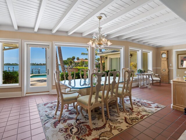 7614 Peninsular Dr, Sarasota, FL 34231 - dining space featuring light tile patterned floors, plenty of natural light, beam ceiling, a chandelier, and a water view