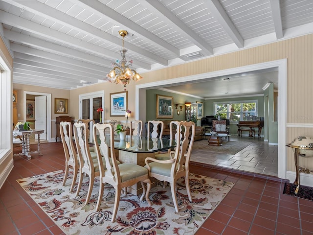 7614 Peninsular Dr, Sarasota, FL 34231 - dining space featuring beamed ceiling, a chandelier, baseboards, dark tile patterned flooring, and a wainscoted wall