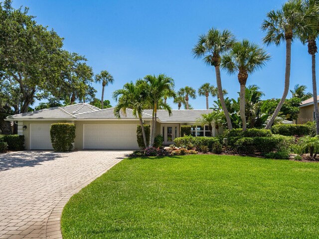 7614 Peninsular Dr, Sarasota, FL 34231 - view of front of property featuring a garage, a front yard, decorative driveway, stucco siding, and a tile roof