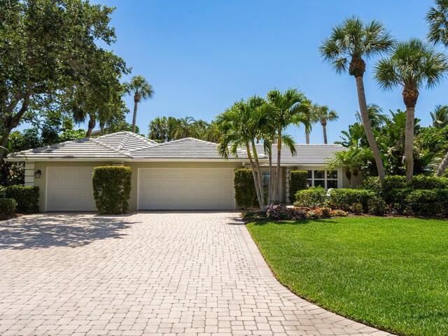 7614 Peninsular Dr, Sarasota, FL 34231 - single story home with an attached garage, a front yard, driveway, a tile roof, and stucco siding