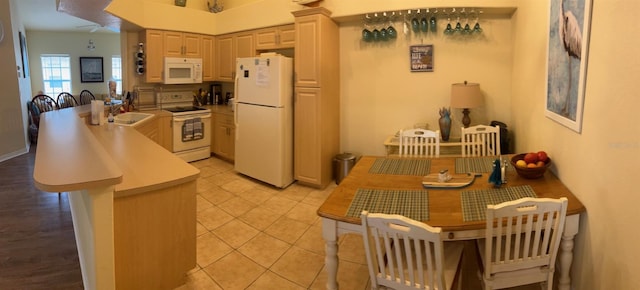 600 Mirabella Cir Unit 201, Venice, FL 34292 - kitchen featuring white appliances, a peninsula, a sink, light tile patterned floors, and light countertops
