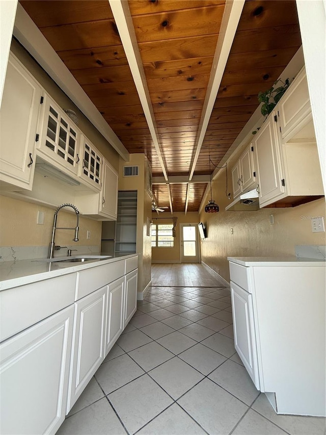6006 Midnight Pass Rd Unit 48, Sarasota, FL 34242 - kitchen with a sink, wooden ceiling with exposed beams, light tile patterned floors, light countertops, and white cabinetry