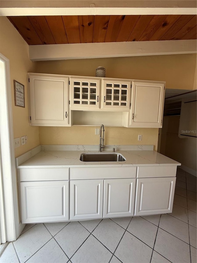 6006 Midnight Pass Rd Unit 48, Sarasota, FL 34242 - kitchen with a sink, light tile patterned floors, wood ceiling, white cabinetry, and light stone counters