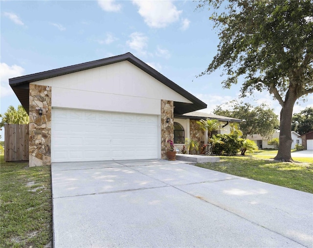 2477 Wood Oak Dr, Sarasota, FL 34232 - ranch-style house with stone siding, an attached garage, driveway, and a front yard