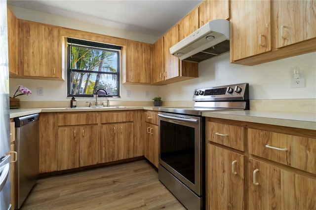 2477 Wood Oak Dr, Sarasota, FL 34232 - kitchen featuring appliances with stainless steel finishes, under cabinet range hood, a sink, light countertops, and light wood-style flooring