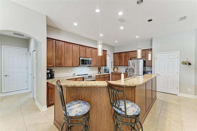 5319 120th Ave E, Parrish, FL 34219 - kitchen with stainless steel appliances, light tile patterned floors, a large island with sink, a breakfast bar, and recessed lighting