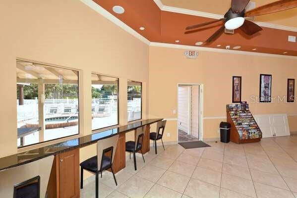 4325 46th Ave W Unit 203, Bradenton, FL 34210 - interior space featuring crown molding, a ceiling fan, light tile patterned floors, a high ceiling, and a tray ceiling